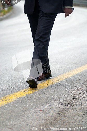 Image of .businessman walking on yellow line