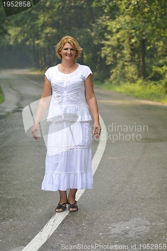 Image of middle age woman walk on white line on road outdoor