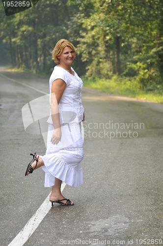 Image of middle age woman walk on white line on road outdoor