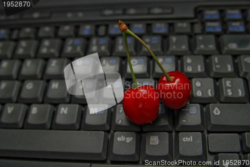 Image of fresh cherry on laptop keyboard 