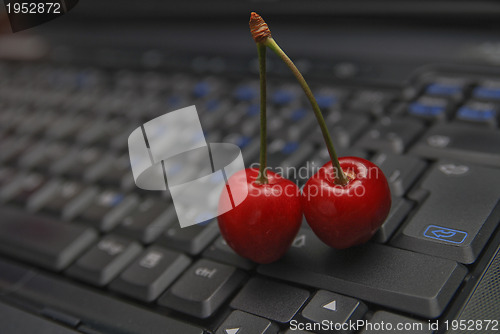 Image of fresh cherry on laptop keyboard 