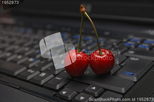 Image of fresh cherry on laptop keyboard 