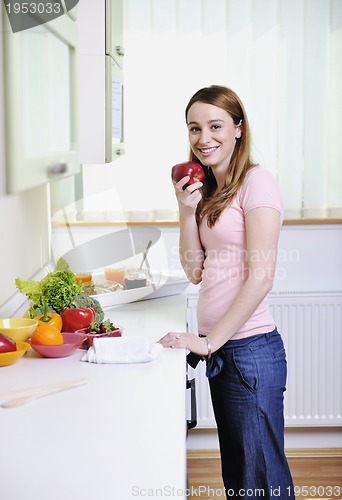 Image of happy young  woman with apple in kitchen
