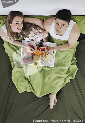 Image of happy young family eat breakfast in bed