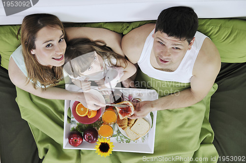 Image of happy young family eat breakfast in bed