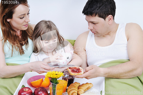 Image of happy young family eat breakfast in bed