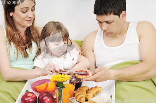 Image of happy young family eat breakfast in bed