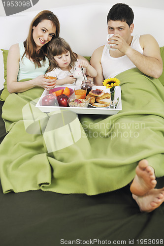 Image of happy young family eat breakfast in bed