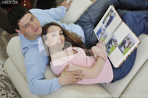 Image of couple looking old pictures in photo album at home