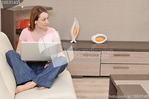 Image of woman relaxing and working on laptop  at home