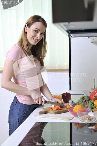 Image of happy young  woman in kitchen