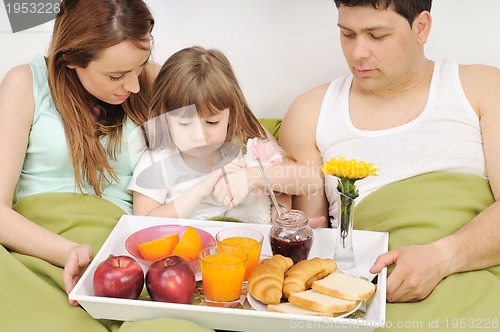 Image of happy young family eat breakfast in bed