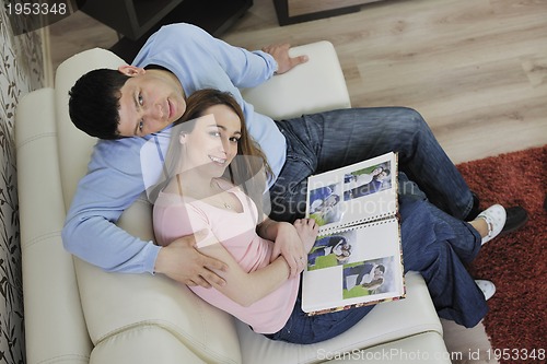 Image of couple looking old pictures in photo album at home