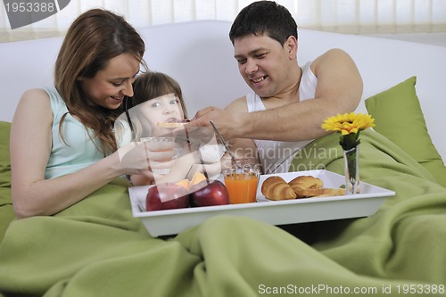 Image of happy young family eat breakfast in bed