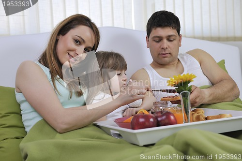 Image of happy young family eat breakfast in bed