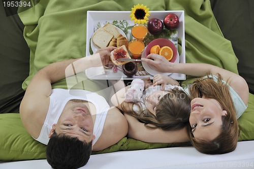 Image of happy young family eat breakfast in bed