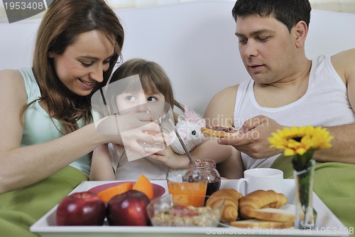 Image of happy young family eat breakfast in bed