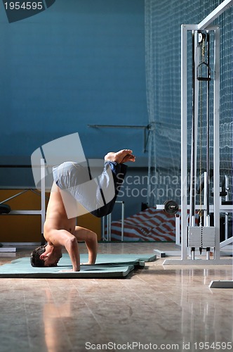 Image of Young man performing  handstand in fitness studio