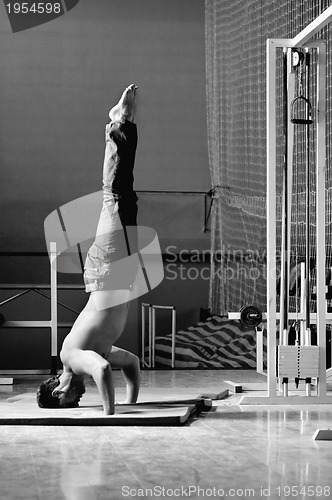 Image of Young man performing  handstand in fitness studio