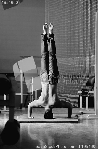 Image of Young man performing  handstand in fitness studio