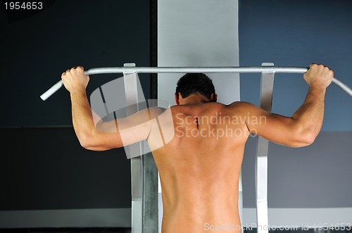 Image of young man with strong arms working out in gym