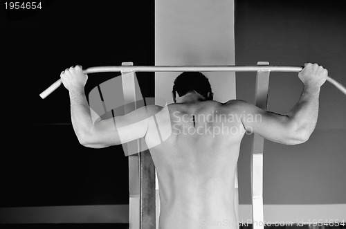 Image of young man with strong arms working out in gym