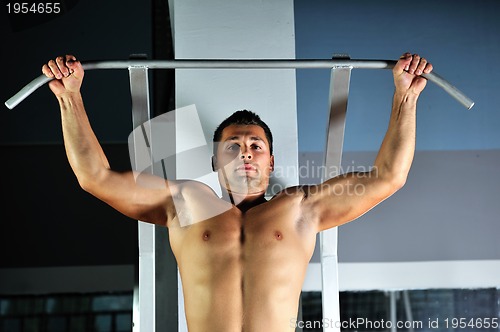 Image of young man with strong arms working out in gym