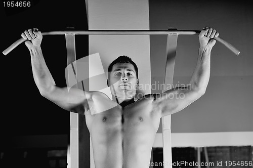 Image of young man with strong arms working out in gym