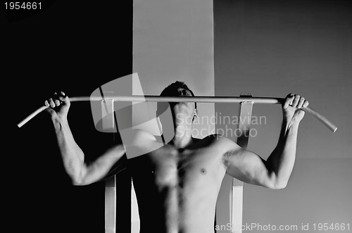 Image of young man with strong arms working out in gym