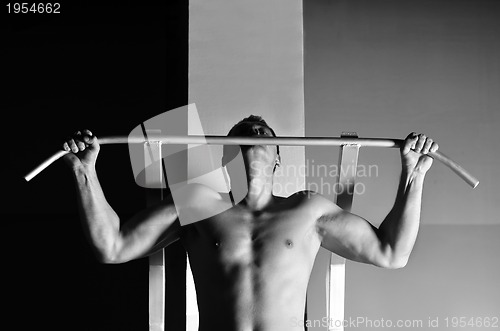 Image of young man with strong arms working out in gym