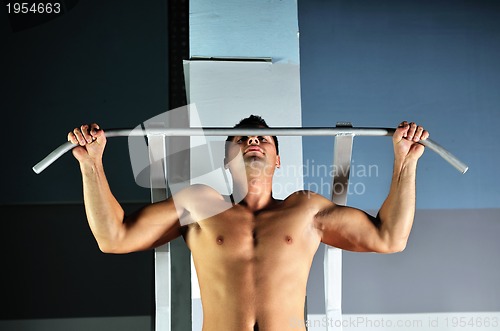 Image of young man with strong arms working out in gym