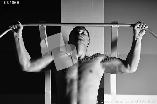 Image of young man with strong arms working out in gym