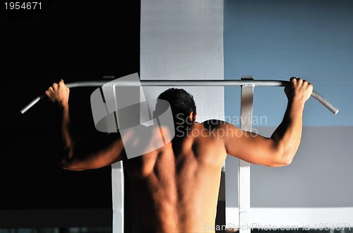 Image of young man with strong arms working out in gym