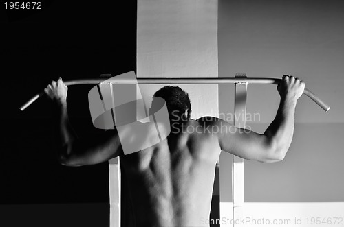 Image of young man with strong arms working out in gym