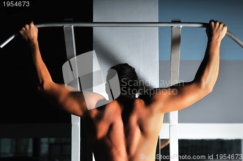 Image of young man with strong arms working out in gym