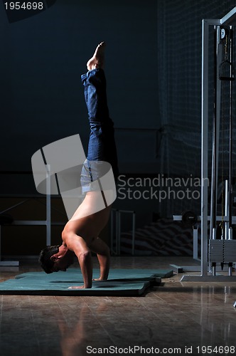 Image of young man performing handstand in fitness studio