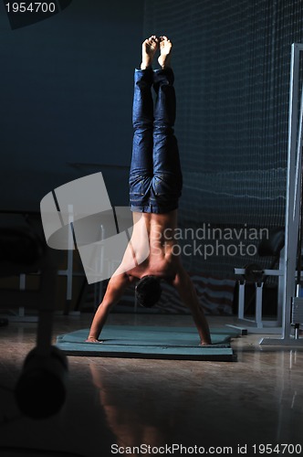 Image of young man performing handstand in fitness studio
