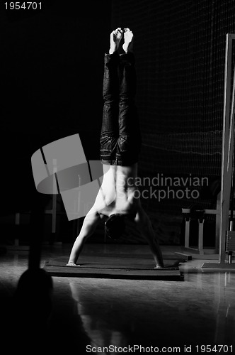 Image of young man performing handstand in fitness studio