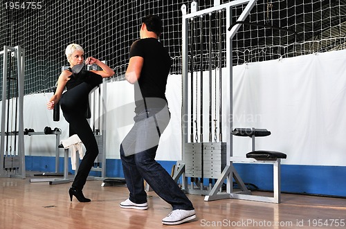 Image of woman in the fitness gim working out with personal trainer