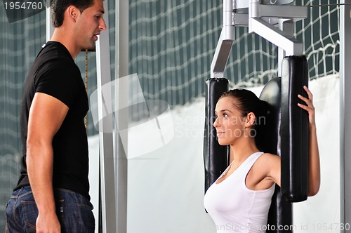 Image of woman in the fitness gim working out with personal trainer