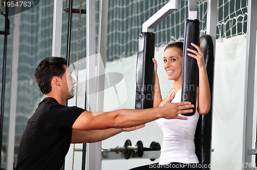 Image of woman in the fitness gim working out with personal trainer