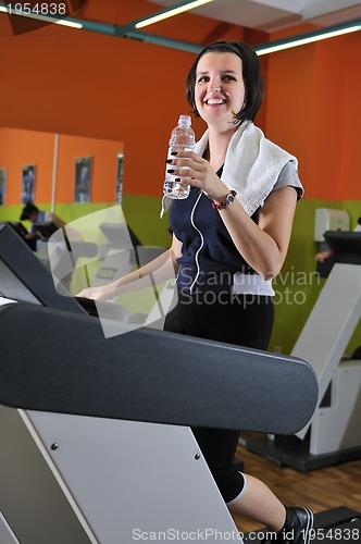 Image of Young woman drinking water while working out