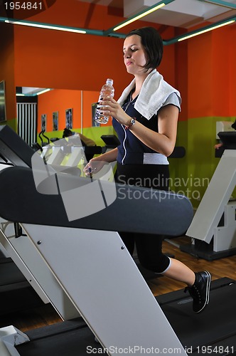 Image of Young woman drinking water while working out