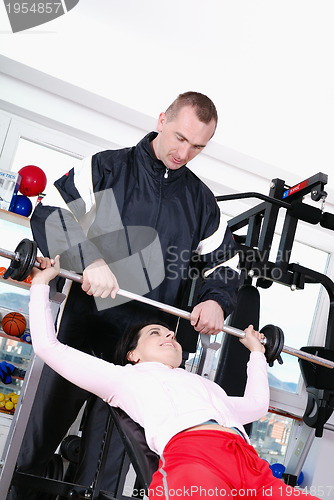 Image of .man assisting woman weitght lifting at a gym 