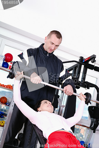 Image of .man assisting woman weitght lifting at a gym 