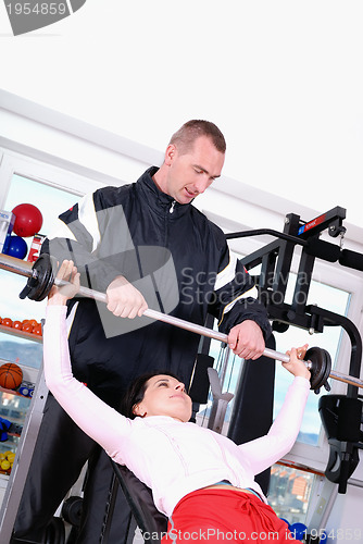 Image of .man assisting woman weitght lifting at a gym 