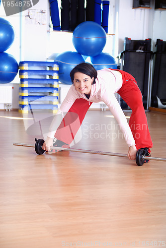 Image of .a young woman weightlifting at gym 