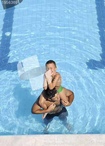 Image of happy father and son at swimming pool