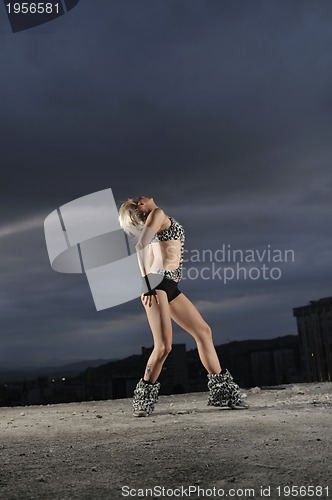 Image of young gogo dancer girl on top of the building with city in backg