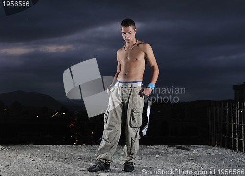 Image of young man dancing and jumping  on top of the building 